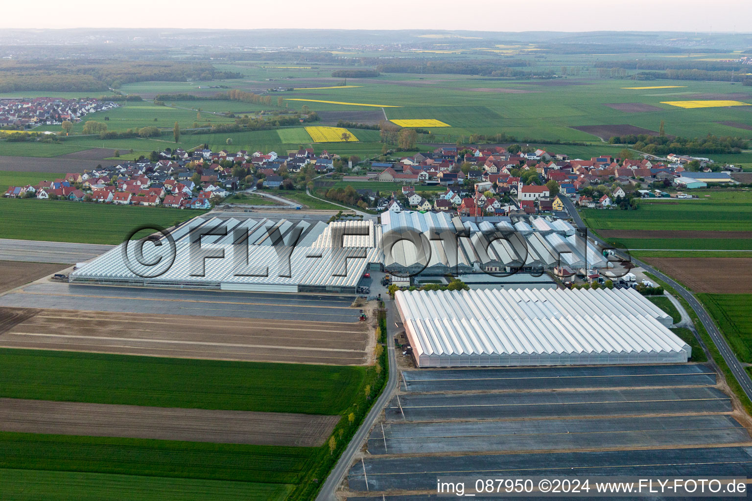 Vue oblique de Toitures en verre dans les rangées de serres pour la floriculture et coupoles d'une installation de biogaz de Gartenbau Gernert à le quartier Oberspiesheim in Kolitzheim dans le département Bavière, Allemagne