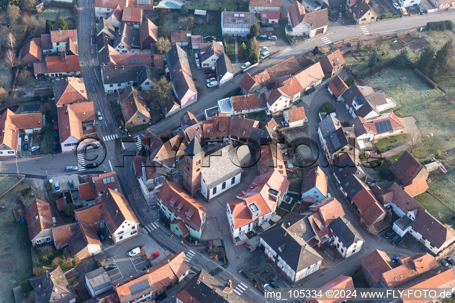 Église fortifiée luthérienne-protestante au centre du village entourée d'un anneau de maisons à Dossenheim-sur-Zinsel dans le département Bas Rhin, France du point de vue du drone