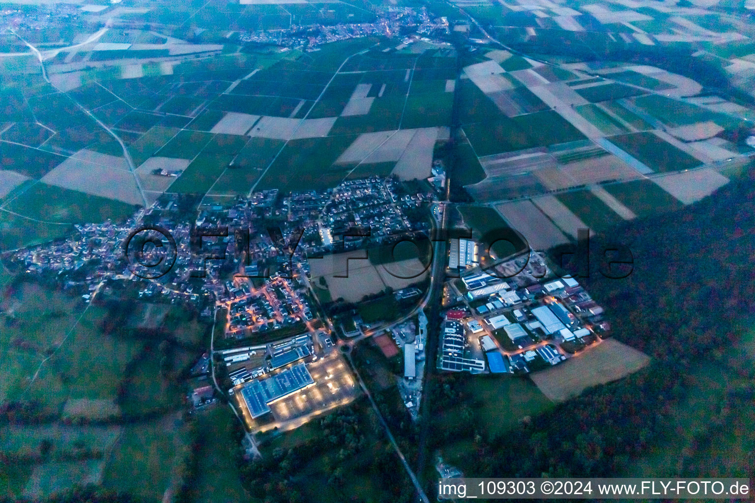 Vue aérienne de Vue de la ville éclairée au crépuscule en bordure des champs agricoles et des zones agricoles à Rohrbach dans le département Rhénanie-Palatinat, Allemagne