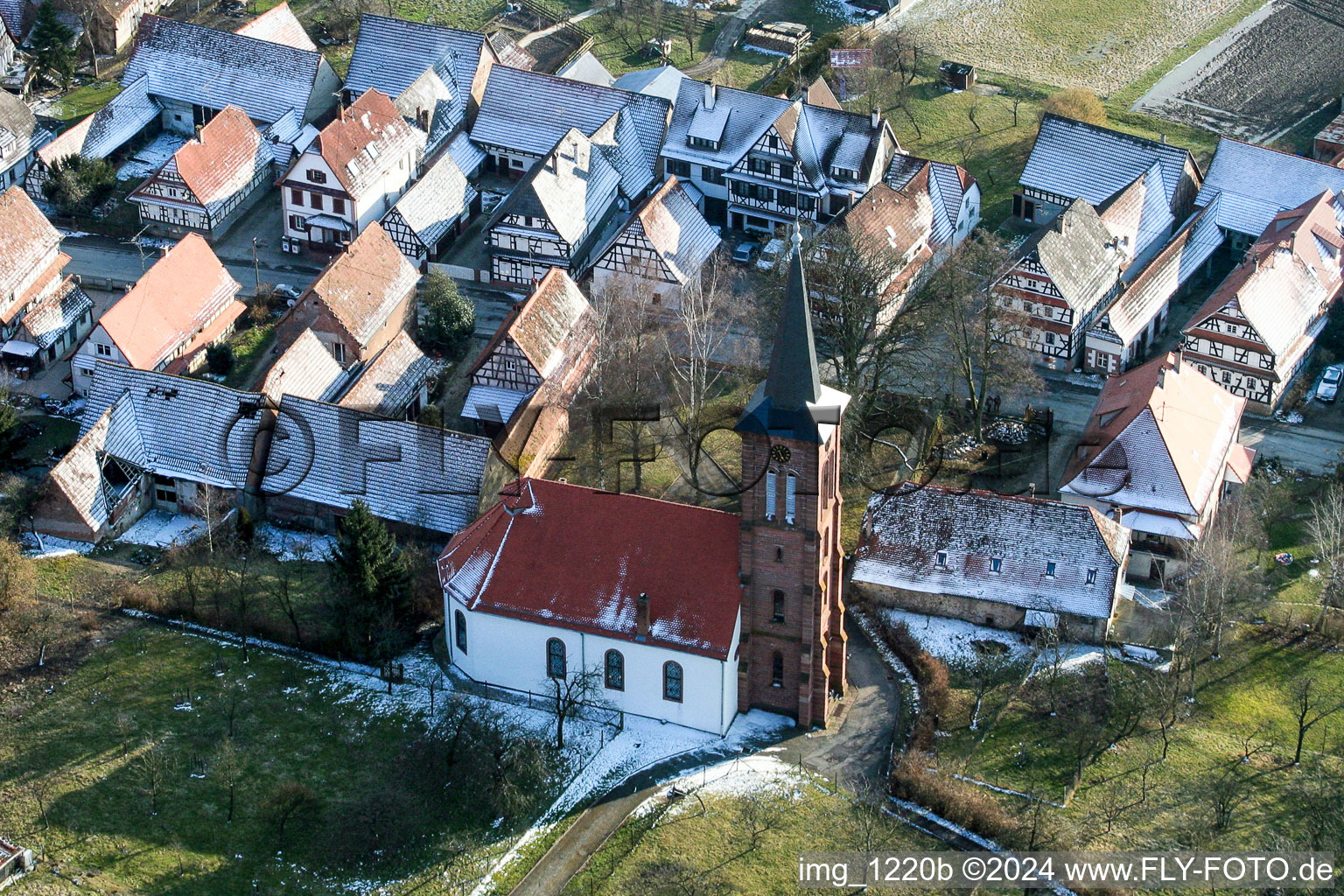 Vue aérienne de Église protestante de Hunspach enneigée au centre du village en hiver à Hunspach dans le département Bas Rhin, France