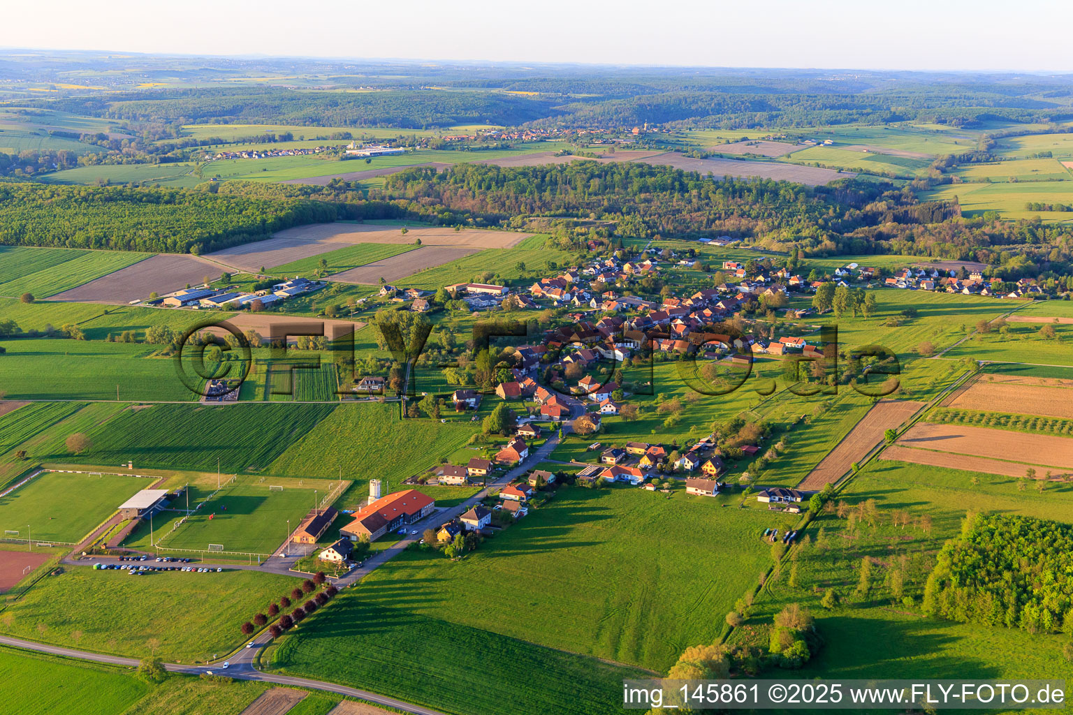 Vue aérienne de Vue du village depuis le sud-ouest avec le terrain de sport ASI Avenir Football à Adamswiller dans le département Bas Rhin, France