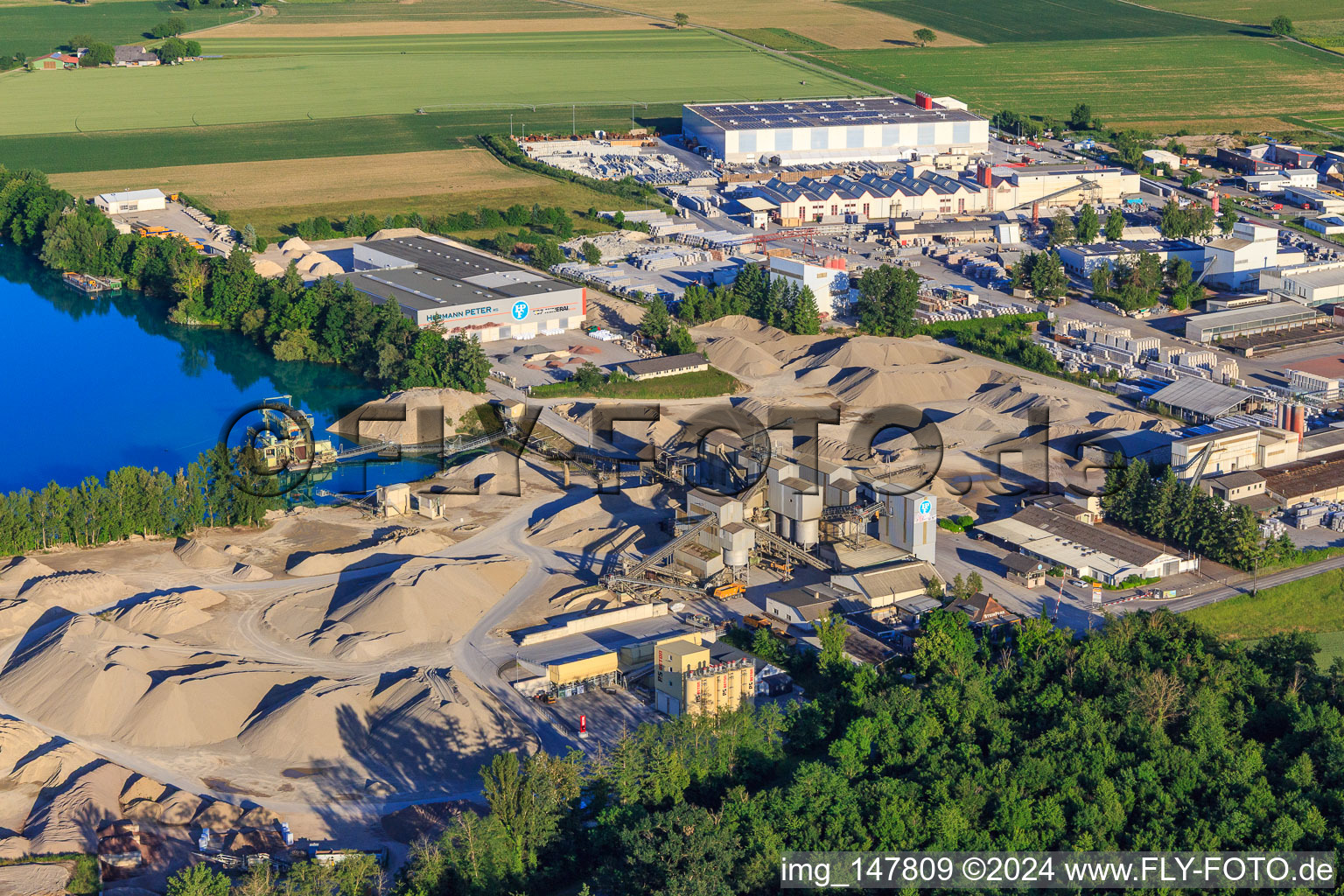 Vue aérienne de Gravière Rimsinger Baggersee / Niederrimsingen avec P & S-Beton GmbH & Co. KG, Birkenmeier Stein + Design GmbH et H+H Kalksandstein GmbH à le quartier Oberrimsingen in Breisach am Rhein dans le département Bade-Wurtemberg, Allemagne