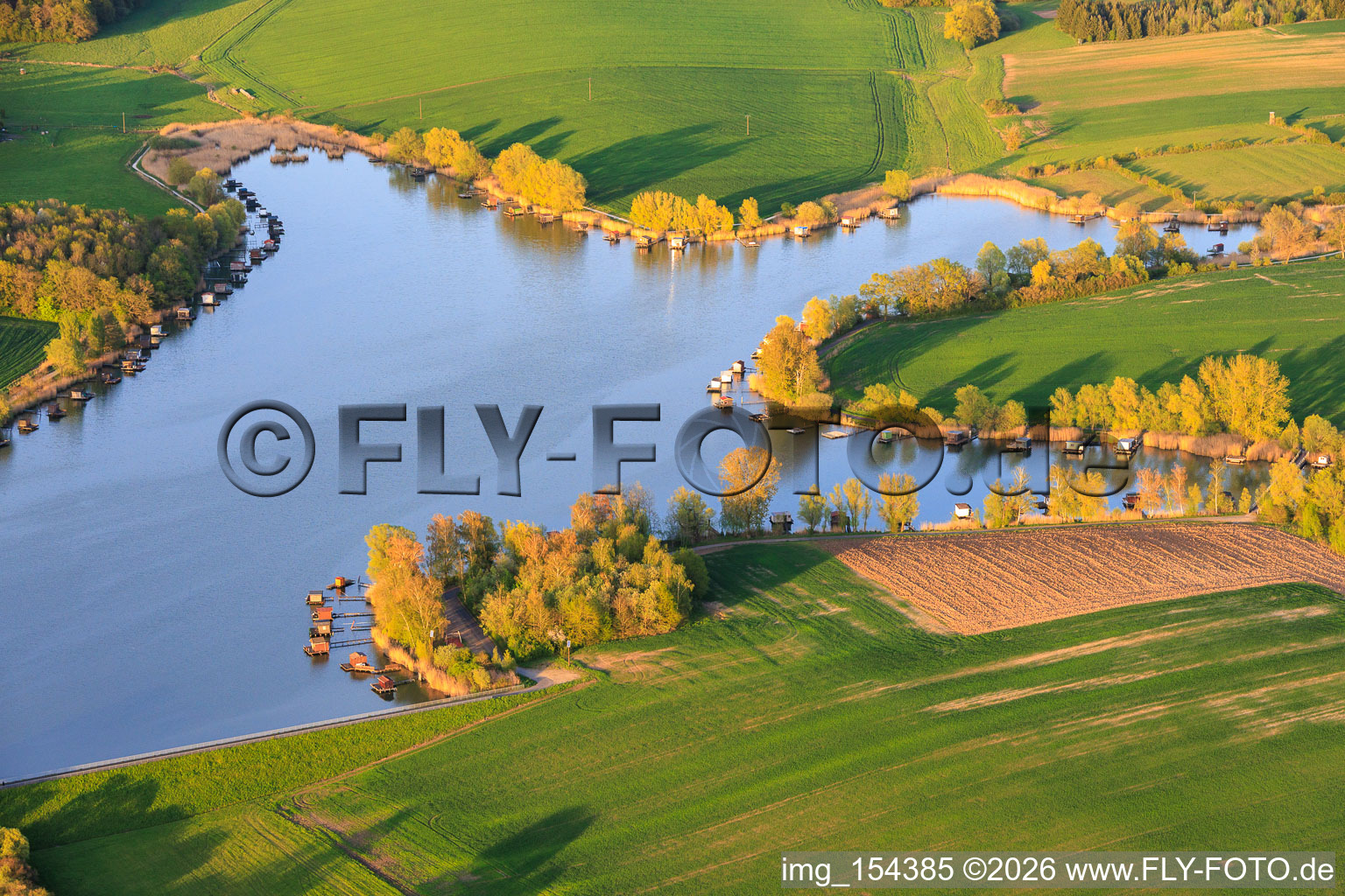 Des promenades en bois bordées de cabanes de pêcheurs longent les rives de l'étang du Welschhof. à Puttelange-aux-Lacs dans le département Moselle, France