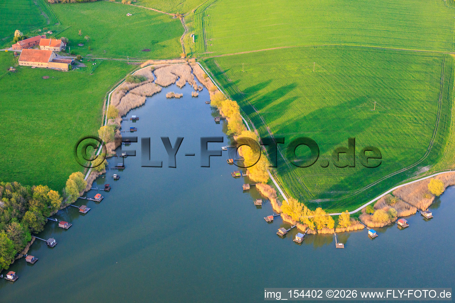 Des promenades en bois bordées de cabanes de pêcheurs longent les rives de l'étang du Welschhof. à Puttelange-aux-Lacs dans le département Moselle, France