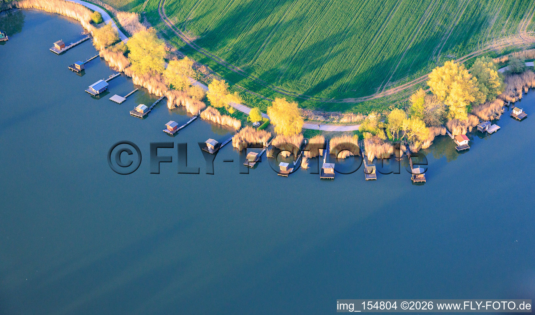 Des promenades en bois bordées de cabanes de pêcheurs longent les rives de l'étang du Welschhof. à Puttelange-aux-Lacs dans le département Moselle, France