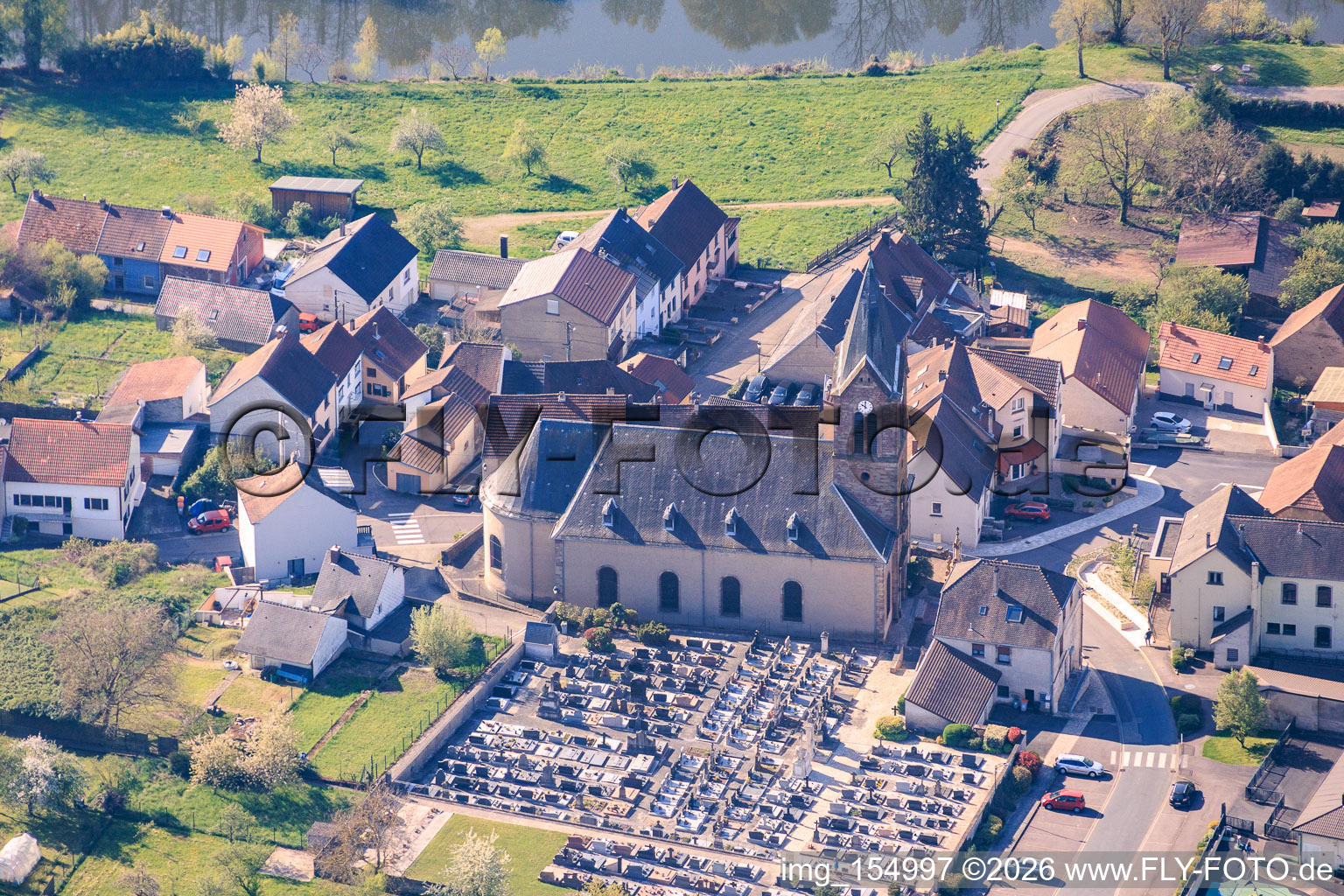 Église et cimetière sur les rives de la Sarre à Sarreinsming dans le département Moselle, France