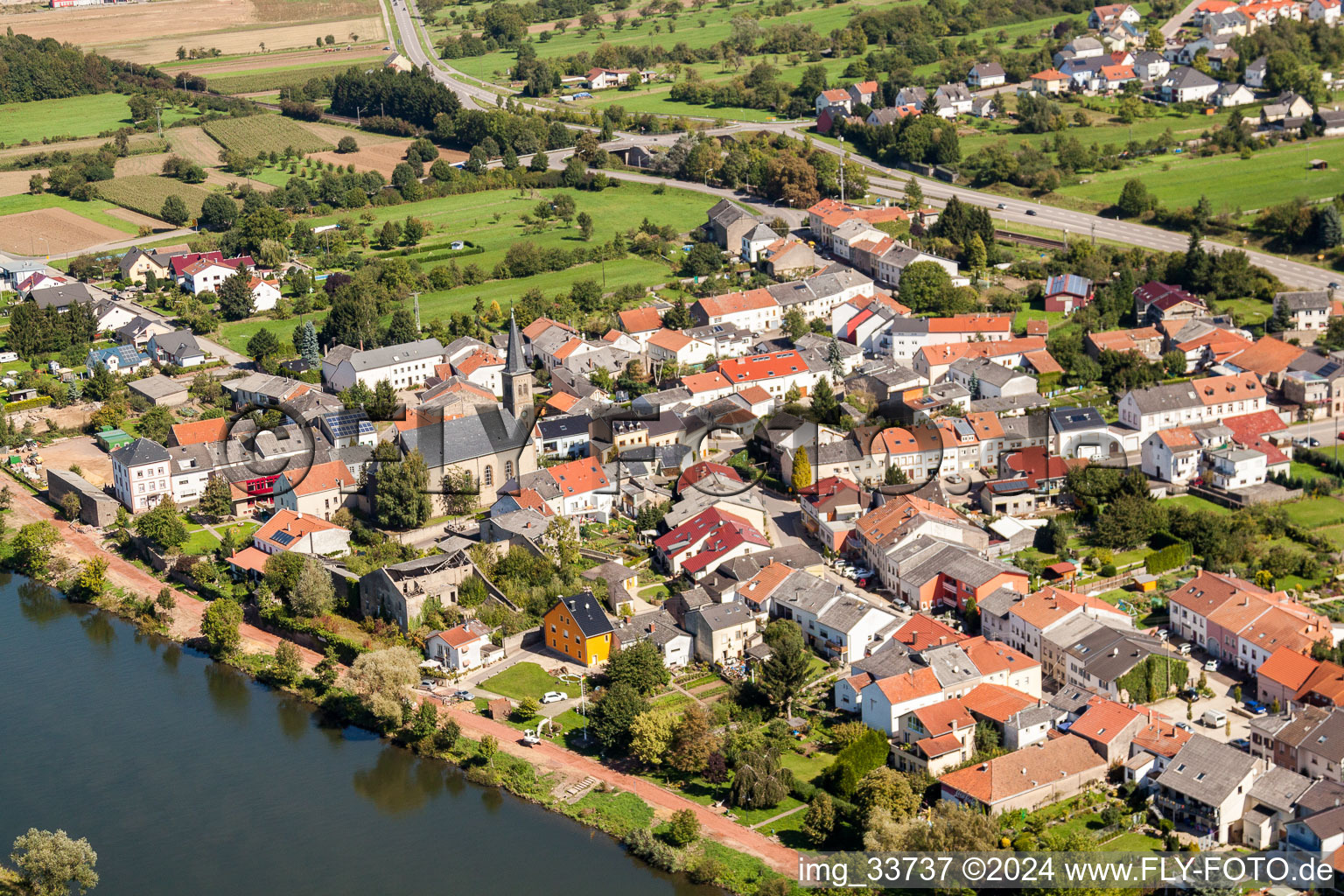 Vue aérienne de Berges de la Moselle avec l'église Saint-Magaretha à le quartier Besch in Perl dans le département Sarre, Allemagne