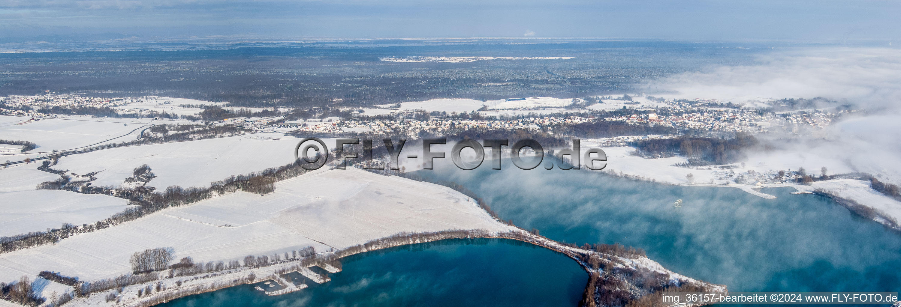 Vue aérienne de Perspective panoramique couverte de neige hivernale derrière les lacs de carrière à le quartier Neulauterburg in Lauterbourg dans le département Bas Rhin, France