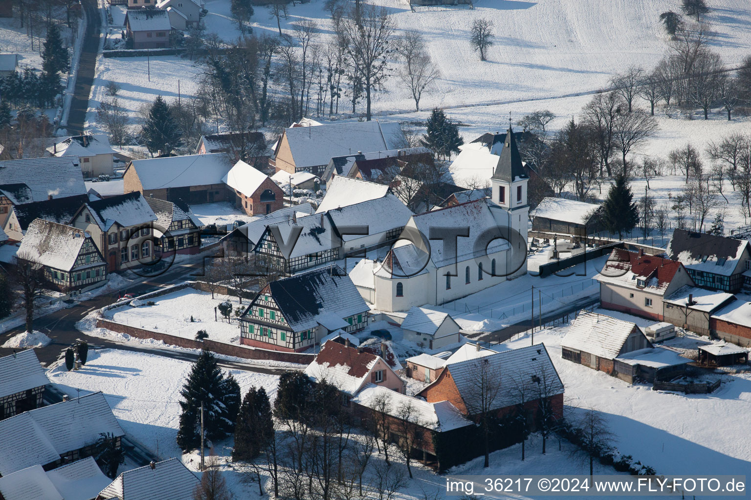 Vue aérienne de Bâtiments d'église enneigés en hiver au centre du village à Eberbach-Seltz dans le département Bas Rhin, France