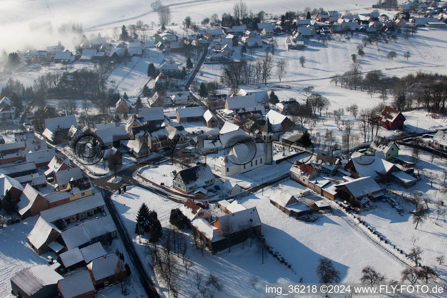 Vue aérienne de Bâtiments d'église enneigés en hiver au centre du village à Eberbach-Seltz dans le département Bas Rhin, France