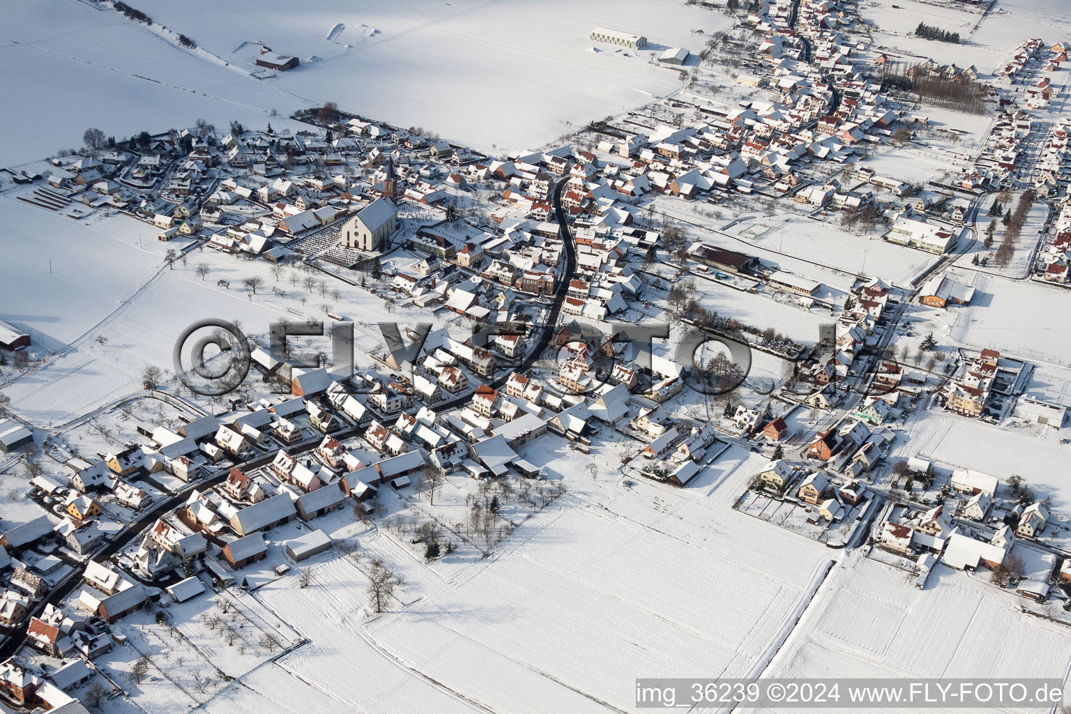 Vue aérienne de Bâtiments d'église enneigés en hiver au centre du village à Schleithal dans le département Bas Rhin, France