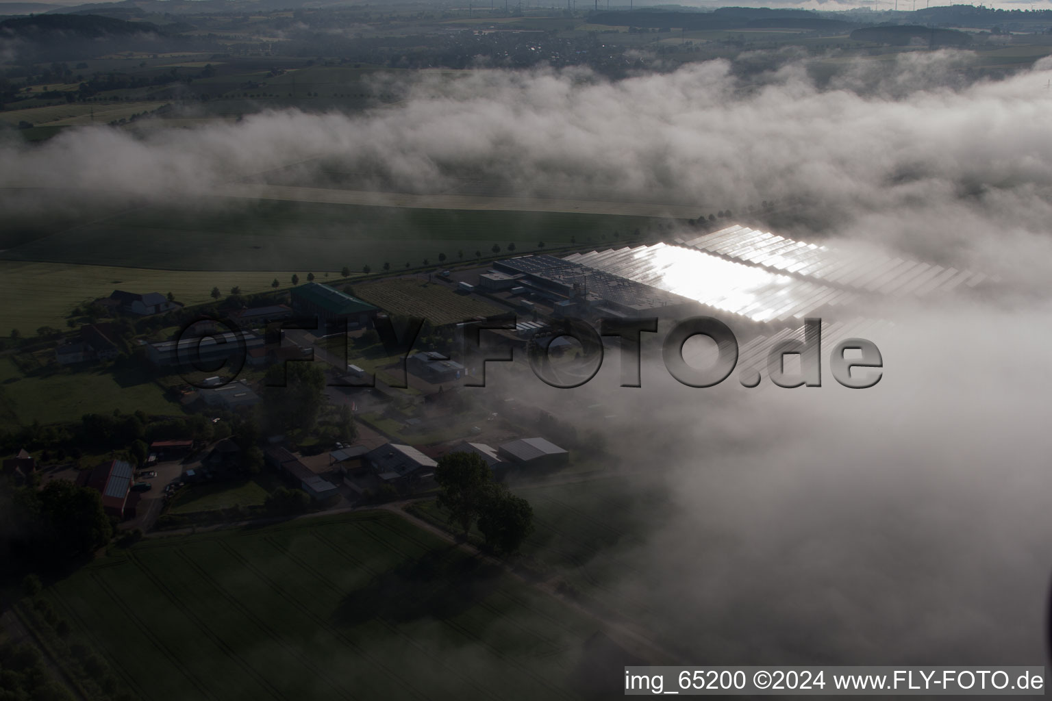 Vue aérienne de En raison des conditions météorologiques, des rangées de panneaux du système photovoltaïque du parc solaire ou de la centrale solaire sont encastrées dans une couche de brouillard à le quartier Bredenborn in Marienmünster dans le département Rhénanie du Nord-Westphalie, Allemagne