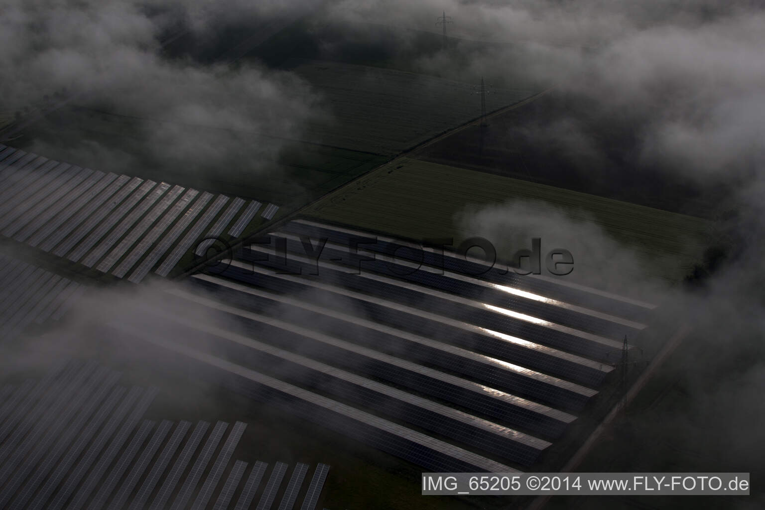 En raison des conditions météorologiques, les rangées de panneaux du système photovoltaïque du parc solaire ou de la centrale solaire du quartier de Bredenborn sont noyées dans une couche de brouillard. à Marienmünster dans le département Rhénanie du Nord-Westphalie, Allemagne d'en haut