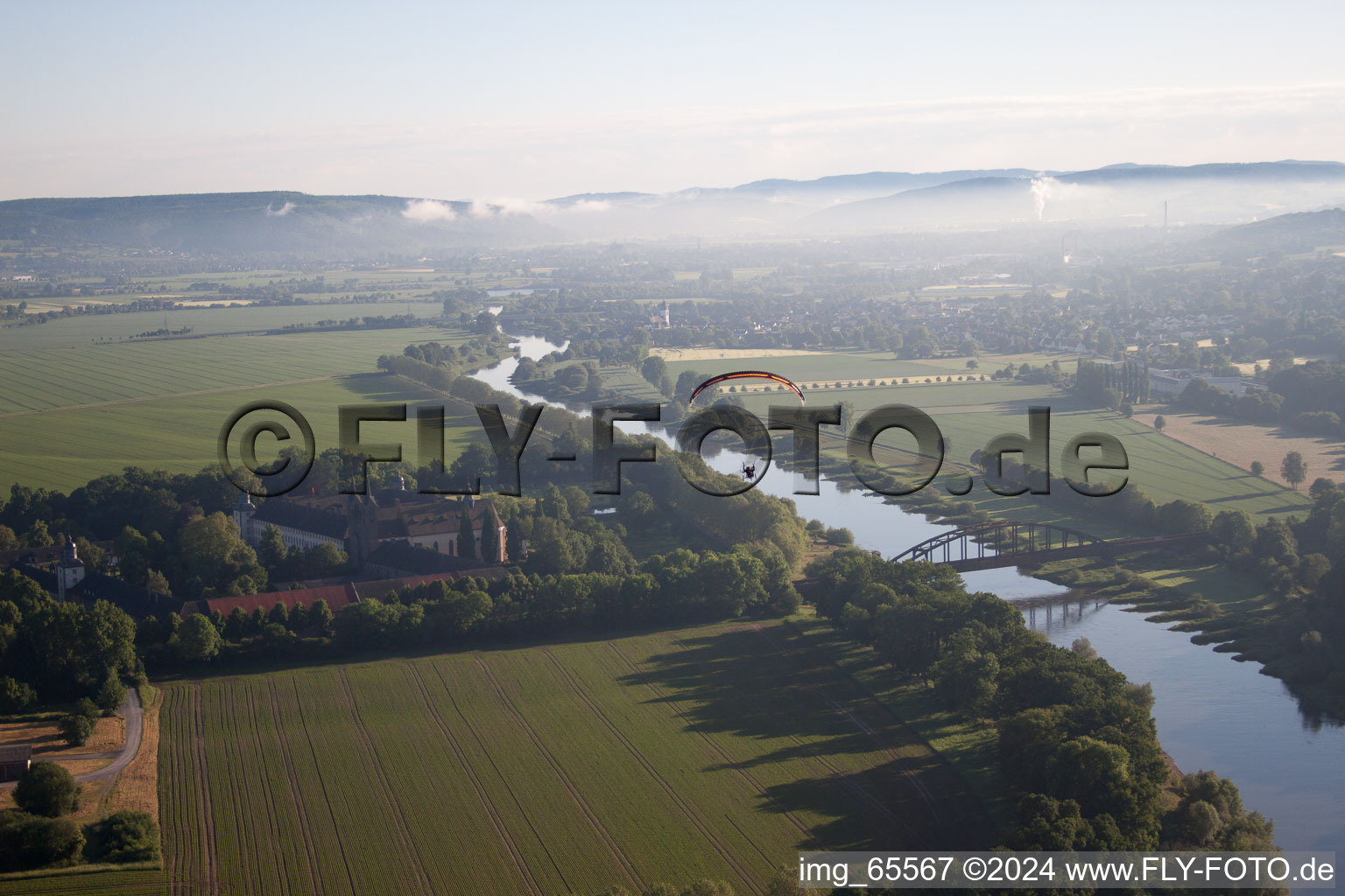 Photographie aérienne de Château/Monastère de Corvey (patrimoine mondial de l'UNESCO) au bord de la rivière - structure de pont sur la Weser à Höxter dans le département Rhénanie du Nord-Westphalie, Allemagne