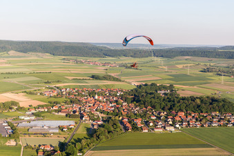Vue aérienne de Parapente au-dessus d'un village en bordure de champs agricoles et de terres agricoles à Rüdenhausen dans le département Bavière, Allemagne