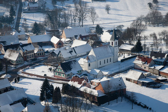 Vue aérienne de Bâtiments d'église enneigés en hiver dans le centre du village à Eberbach-Seltz dans le département Bas Rhin, France