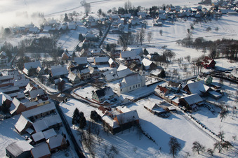 Vue aérienne de Bâtiments d'église enneigés en hiver dans le centre du village à Eberbach-Seltz dans le département Bas Rhin, France
