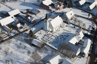 Bâtiments d'église enneigés en hiver dans le centre du village à Eberbach-Seltz dans le département Bas Rhin, France d'en haut