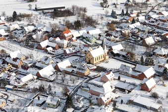 Vue aérienne de Bâtiments d'église enneigés en hiver dans le centre du village à Oberlauterbach dans le département Bas Rhin, France