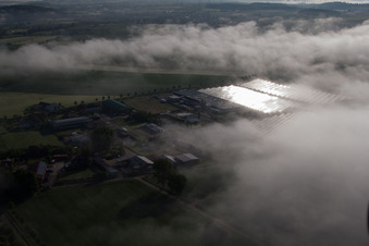 Vue aérienne de Rangées de panneaux du système photovoltaïque du parc solaire ou de la centrale solaire noyées dans une couche de brouillard due aux intempéries à le quartier Bredenborn in Marienmünster dans le département Rhénanie du Nord-Westphalie, Allemagne
