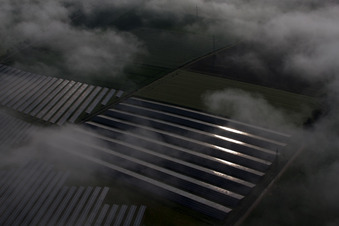 Rangées de panneaux du système photovoltaïque du parc solaire ou de la centrale solaire noyées dans une couche de brouillard due aux intempéries à le quartier Bredenborn in Marienmünster dans le département Rhénanie du Nord-Westphalie, Allemagne d'en haut