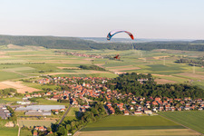 Vue aérienne de Parapente au-dessus d'un village en bordure de champs agricoles et de terres agricoles à Rüdenhausen dans le département Bavière, Allemagne