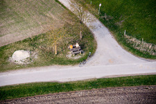 Vue aérienne de Un couple de personnes âgées est assis sur un banc au bord d'un carrefour et fait signe de la main dans le quartier de Stillern à Raisting dans le département Bavière, Allemagne